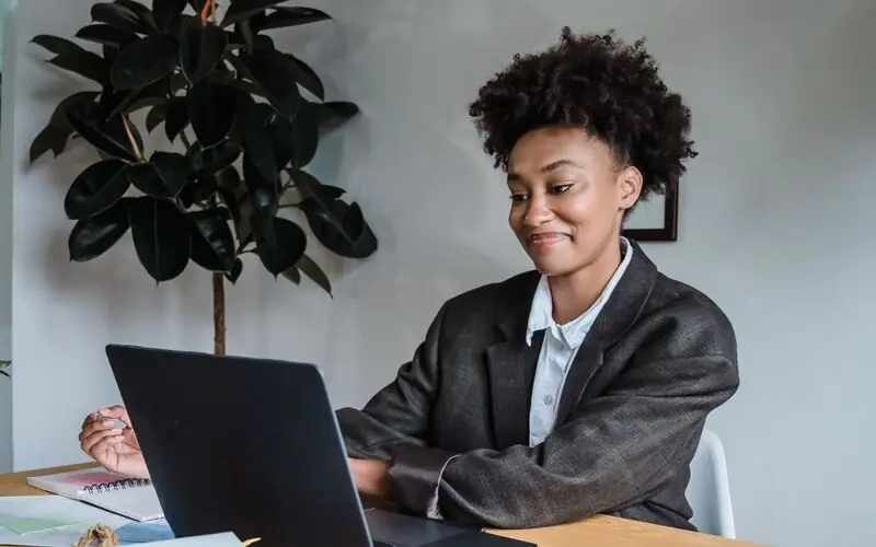 Professional working on a laptop at a desk with notebooks and papers