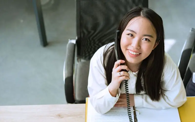 Smiling office worker answering a customer call on a desk phone
